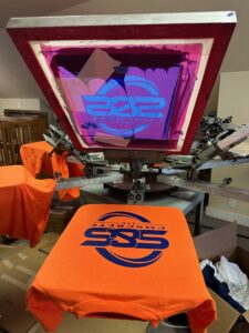 custom screen printing on safety orange sweater at The Print Plug